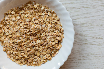 Dry oats in bowl on wooden background