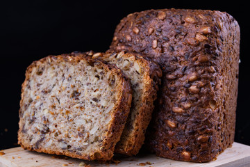 Tasting bread with seeds on a wooden board. Fresh dark bread on the kitchen table.