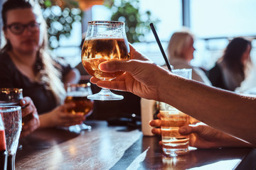 Young guy holding a glass of beer sitting in a caf with his friends
