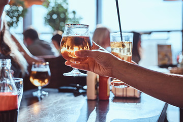 Young guy holding a glass of beer sitting in a caf with his friends