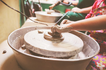 Young potter hands working with clay on pottery wheel