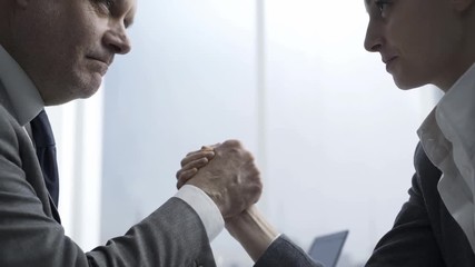 Business competitors arm wrestling on the office desk - Powered by Adobe