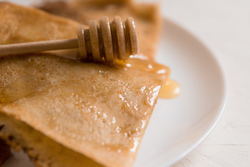 traditional Russian pancakes with honey on a light background.carnival.copy spase.pancake week.pancakes with honey syrup on a white plate 