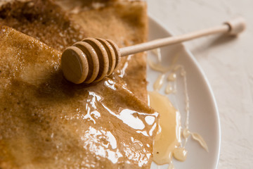 traditional Russian pancakes with honey on a light background.carnival.copy spase.pancake week.pancakes with honey syrup on a white plate 