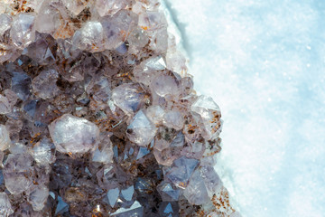 Amethyst natural crystal cluster with Goethite inclusions from Brazil on white snow at a sunny winter day.