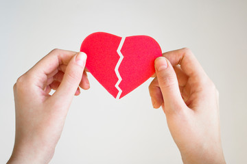 Woman hands holding a broken heart shape.