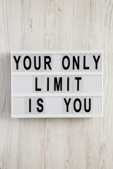 'Your only limit is you' word on modern board on a white wooden surface, top view. From above, flat lay, overhead.