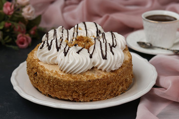 Honey sponge cake with butter cream located on a dark background