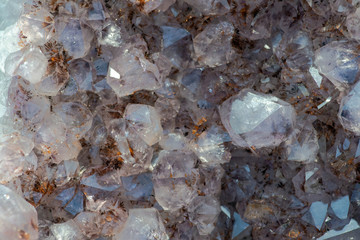 Amethyst natural crystal cluster with Goethite inclusions from Brazil on white snow at a sunny winter day.
