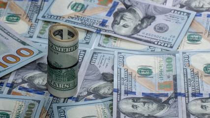 Fototapeta premium 100 dollar bills twisted into tube and tied with an elastic band. white background.