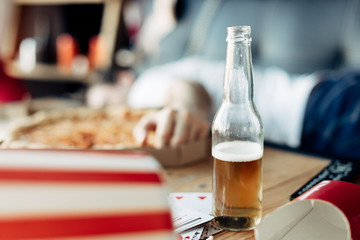 selective focus of bottle of beer with man on background