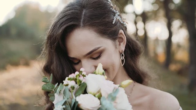 Portrait of attractive bride smiling and sniffing flowers at camera