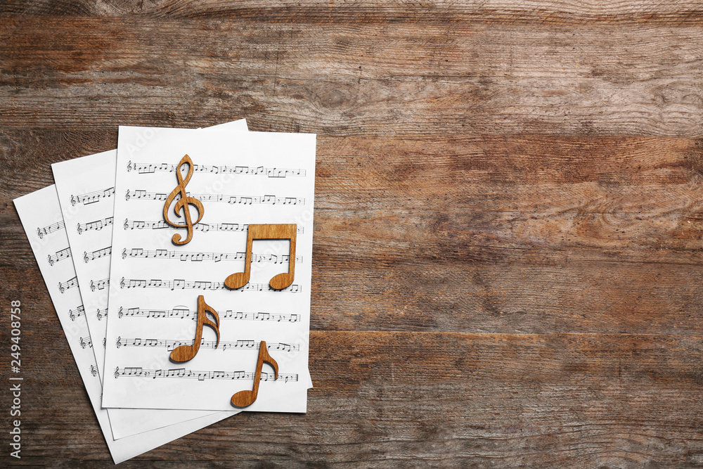 Sticker Music notes with sheets on wooden background, flat lay. Space for text