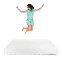 Young woman jumping on mattress against white background