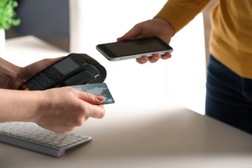 Women using modern payment terminal at table indoors, closeup