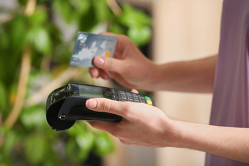 Woman using modern payment terminal indoors, closeup