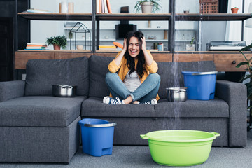 Stressed woman screaming with closed eyes during water leak in living room
