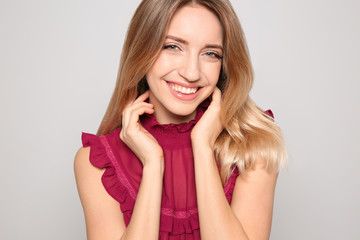 Fototapeta premium Portrait of beautiful smiling woman in stylish clothes on light background