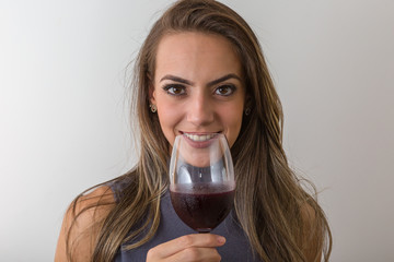 Smiling young woman sommelier with red wine in glass over white background