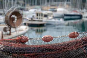 Red fishing net with red buoys. Blurred background on the harbor.