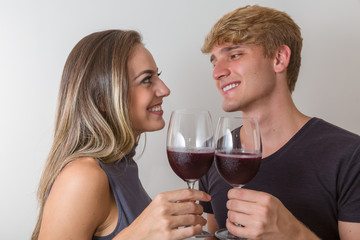 Joyful young couple making a toast with glasses of wine isolated on white background