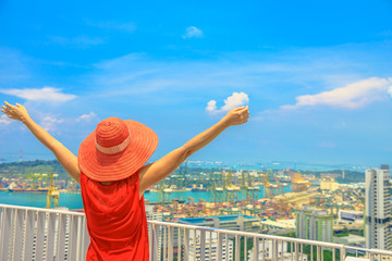 Carefree woman enjoys panorama from one of Singapore's tallest skyscrapers in Chinatown. Aerial...