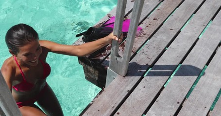 Sexy woman on vacation travel snorkeling swimming on beach looking at camera smiling happy wearing red bikini and pink snorkeling fins coming out of water