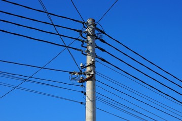 part of a gray concrete pillar with black wires against a blue sky