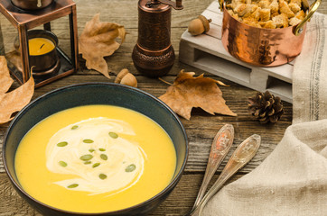 Pumpkin cream soup. Homemade fresh pumpkin cream soup served with croutons on a rustic background, autumn decoration