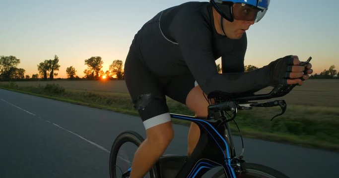 A Cyclist riding along a road at sun down breathing deeply.