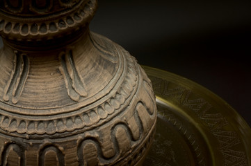 Close-up Antique greek vase on golden plate on black slate table, dark background with slight shadow on the plate