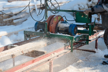 Sawing boards on the sawmill. Cook lumber in winter. Work on the sawmill.