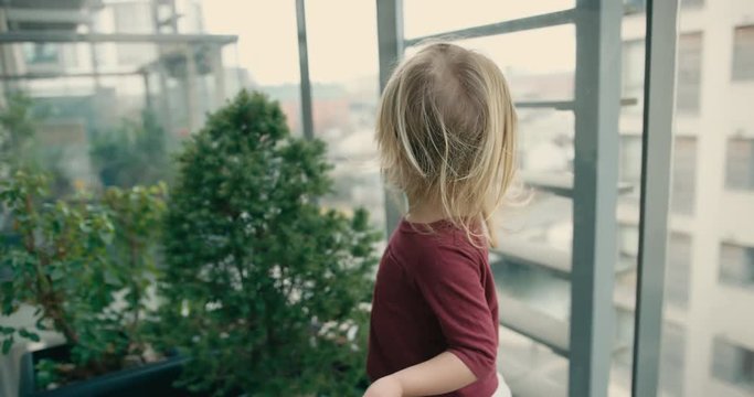 Little toddler playing on the balcony of high ris ein the city