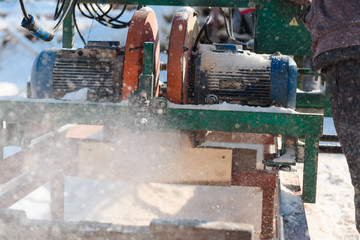 Sawing boards on the sawmill. Cook lumber in winter. Work on the sawmill.