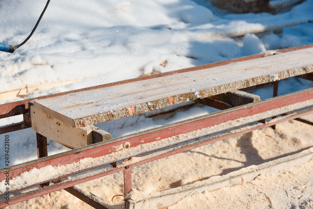 Wall mural Sawing boards on the sawmill. Cook lumber in winter. Work on the sawmill.