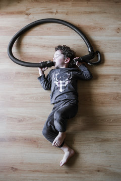 Un enfant allong&eacute; par terre avec un aspirateur