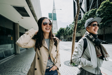 beautiful asian friends having fun laughing talking chatting while walking on street in san...