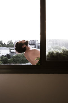 Homme torse nu dans le balcon, vue &agrave; travers la fen&ecirc;tre