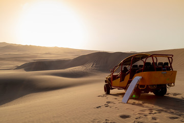 Sand boarding ,Dune Buggy parked in the desert during sunset at Huacachina Oasis in Ica, Peru.