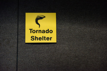 Single bright yellow Tornado Shelter warning sign, designating a safe room area