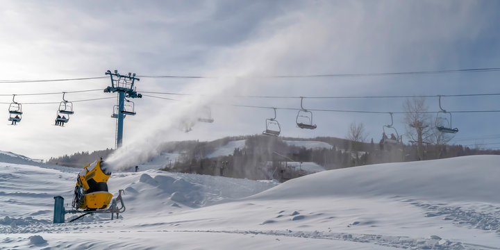 Snow gun against ski lifts and cloudy sky in Utah