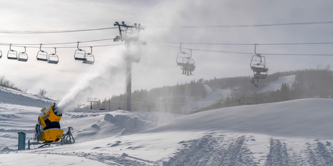 Sunny day in Utah with snow cannons and ski lifts