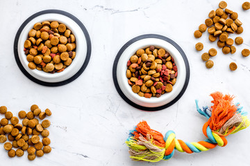 Animal food in bowl on white stone background top view