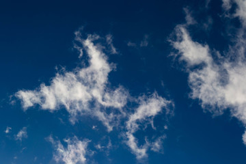 Fototapeta na wymiar Smoky clouds float across a blue afternoon sky.