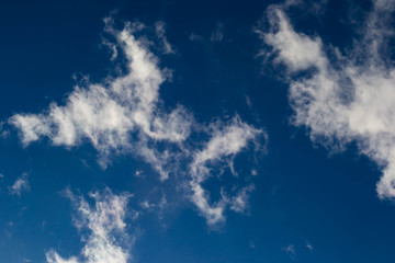 Smoky clouds float across a blue afternoon sky.