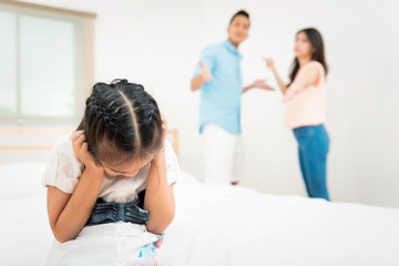 Fototapeta premium Family problem and child with background at quarrel of parents. Sad little girl is unhappy while in the bed room and cry against arguing parents at home or Conflict happened in the family