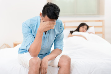 Husband unhappy and disappointed in the erectile dysfunction during sex while his wife sleeping on the bed. Sexual Problems in Men. - obrazy, fototapety, plakaty