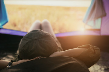 Young woman lying in tent or sleeping on bag with a sunset view on mountains and lake, Camping with Sunset in base camp, One Activity Relaxing in summer