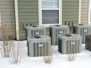 Air conditioner compressors outside the apartment building in winter snow
