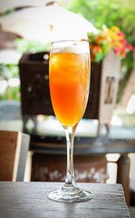 Fresh orange juice in the wine glass on wooden table outdoors nature background